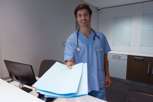 Front view of male surgeon standing with document at desk in hospital 