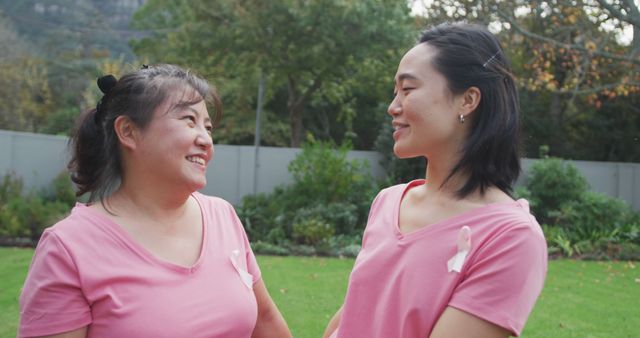 Portrait of happy asian mother embracing adult daughter in garden, wearing pink t shirts. happy family spending quality time at home together.