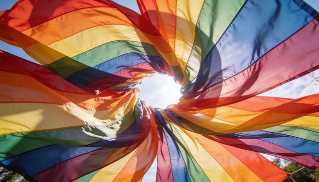 Backlit swirling rainbow fabric vortex canopy creating colorful outdoor sculpture festival