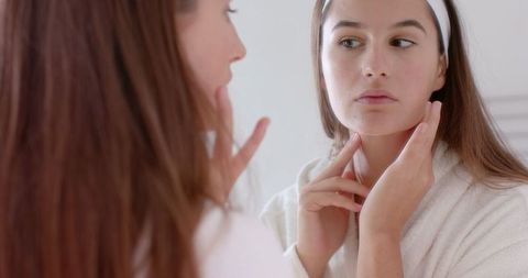 Woman Analyzing Skin in Bathroom Mirror for Skincare Routine