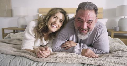 Joyful Mature Couple Relaxing on Bed at Home