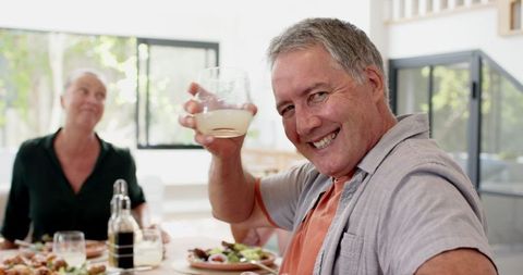Senior Friends Toasting with Joyful Laughter at Dining Table
