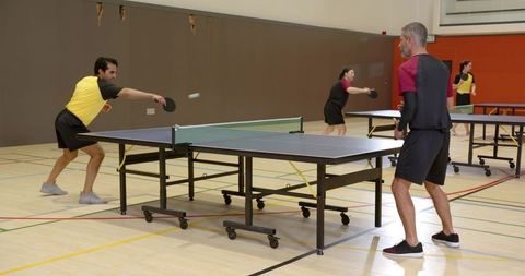 Active table tennis doubles match in gymnasium