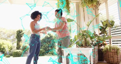 Mother and daughter passing ceramic plant on sunny porch surrounded by lush greenery