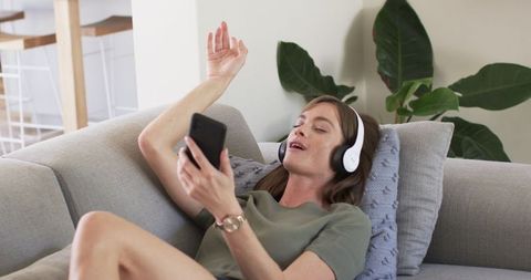 Caucasian Woman Enjoying Music on Couch, Relaxed Home Atmosphere