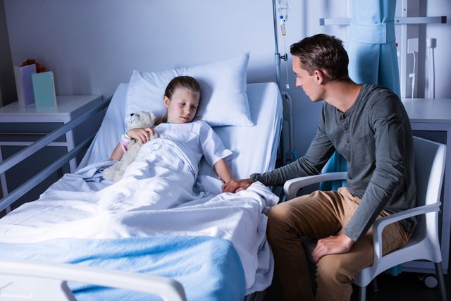 Father sitting beside her daughter lying on a hospital bed - Download Free Stock Photos Pikwizard.com