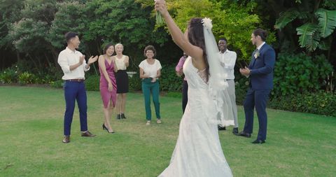 Bride groom dancing celebrating wedding with friends in garden
