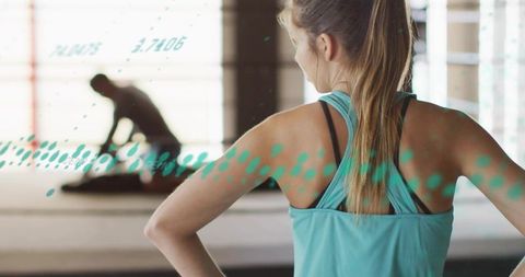 Woman in teal tank watching partner stretch in bright gym with turquoise overlay