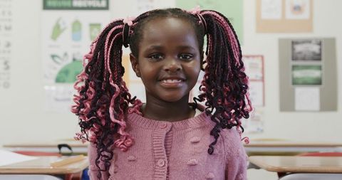 Young girl smiling in classroom with recycling education theme