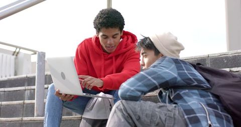 Multiracial Students Collaborating on Laptop on Campus Steps Studying Together Outdoors