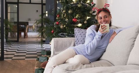 Woman Enjoying Coffee on Sofa Beside Christmas Tree