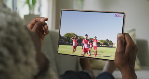 Man Watching Soccer Teams on Tablet in Relaxed Setting