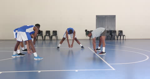 Basketball Players Stretching on Indoor Court Preparing for Training