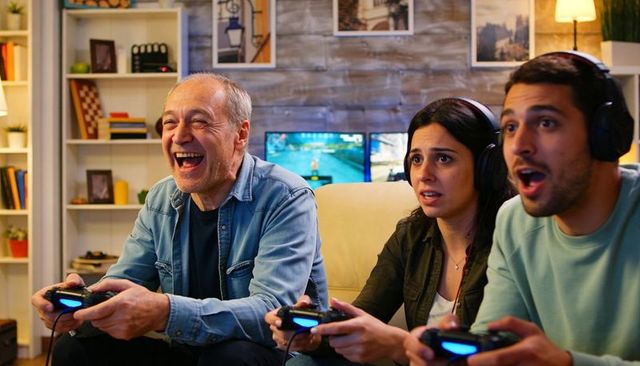 Multigenerational family playing video games on couch laughing and cheering cozy gaming night