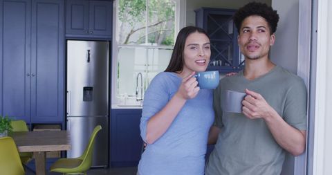 Happy Biracial Couple Drinking Coffee Together in Kitchen