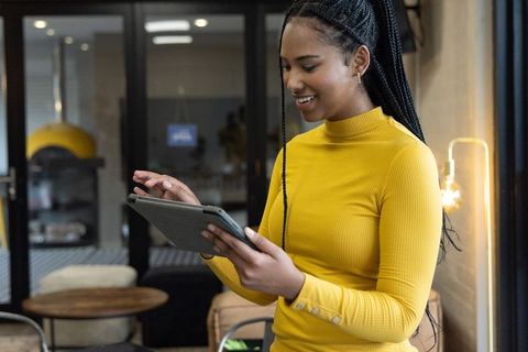 African american woman working on tablet in coworking cafe with warm minimalist interior