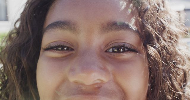 Happy biracial girl face close up in the sun. Childhood, summer, vacations, outdoors and free time, unaltered.