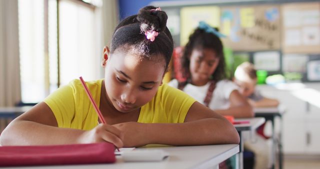 Young girl concentrating on taking notes at school. Ideal for content about education, academic focus, and classroom environment. Useful for educational websites, school advertisements, and articles on childhood learning.