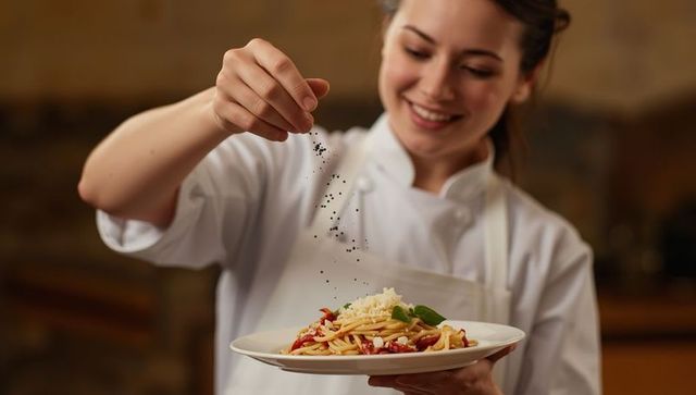 Chef enjoying preparing gourmet pasta dish in restaurant kitchen