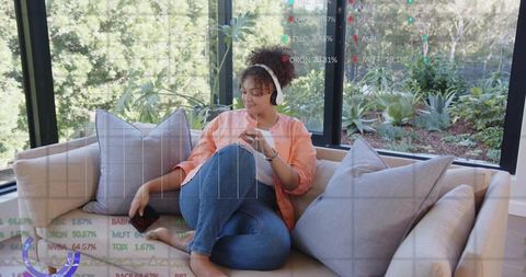 Relaxing woman listening with headphones checking phone and tablet with market charts overlay