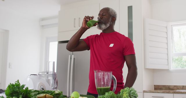 Senior man enjoying healthy green smoothie in modern kitchen. Perfect for promoting healthy living, nutritious recipes, wellness, senior fitness, and health-conscious lifestyles.