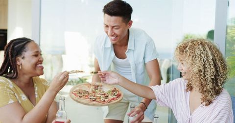 Diverse Friends Laughing and Enjoying Pizza at Home Gathering