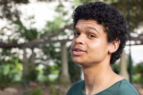 Young african american man turning toward camera in sunlit garden pergola portrait