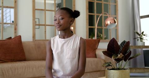 African girl posing confidently on beige sofa in modern chic sunlit living room