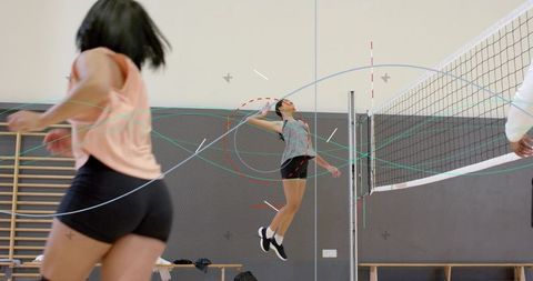 Female volleyball player jumping for spike during indoor team drill coach signaling