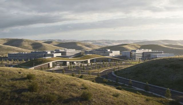 Modern research campus nesting on rolling grassy hills with undulating green roof and glass facades