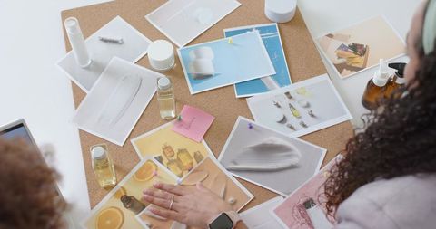 Creative team arranging skincare product moodboard on corkboard for branding and packaging