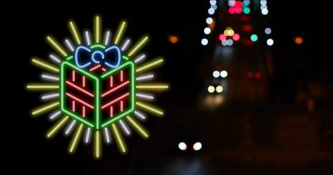 Festive neon gift box illuminated on busy night