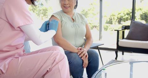 Nurse Administering Vaccination to Senior Woman at Home