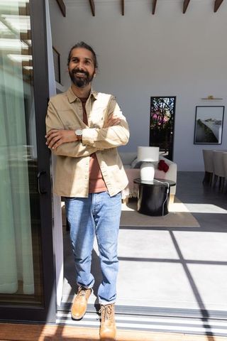 Relaxed Indian Man in Modern Home Standing in Sunlit Doorway