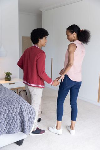 Young couple sharing tender moment by bed while packing suitcase for trip departure