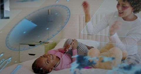 Caregiver clapping with child on bed surrounded by holographic learning graphics