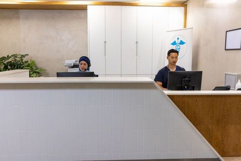Multicultural medical reception team working at clinic desk with headsets and computers