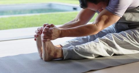 Mature Man Stretching Outdoors on Yoga Mat