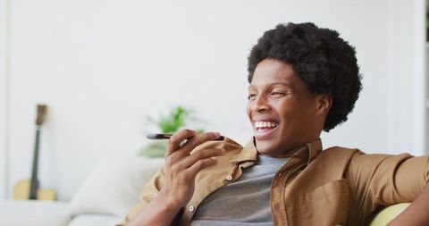 Happy Man Using Smartphone Voice Assistant Relaxed at Home
