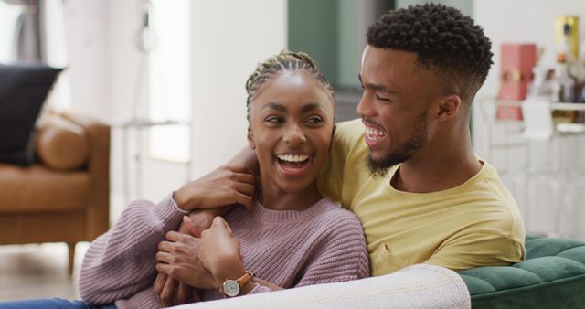 Happy african american couple talking and hugging on sofa. Lifestyle, relationship, spending free time together concept.