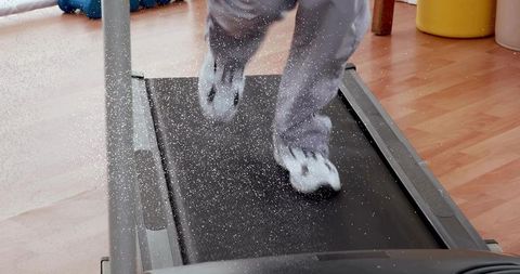 Child running on home treadmill kicking up dust, active indoor workout with sneakers