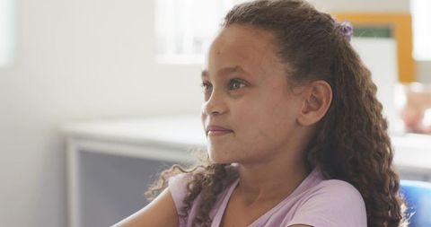 Preteen african american girl sitting at school desk looking thoughtful and calm