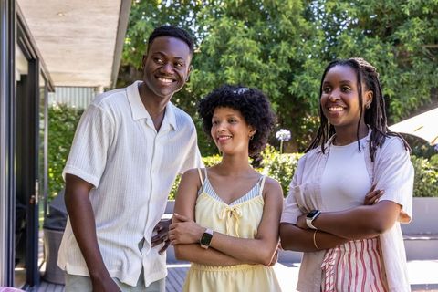African american friends standing on backyard deck smiling while wearing smartwatches