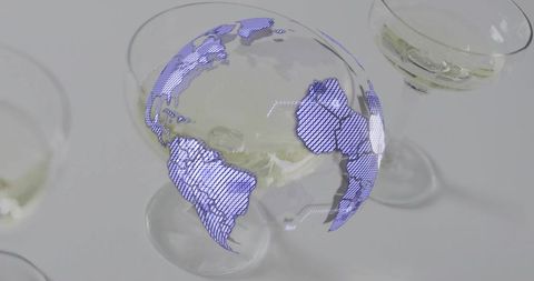 Holographic violet-blue globe hovering above coupe glass containing pale cocktail for futuristic bra