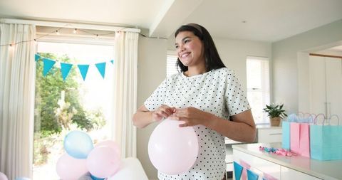 Joyful Woman Inflating Balloon During Celebration at Home