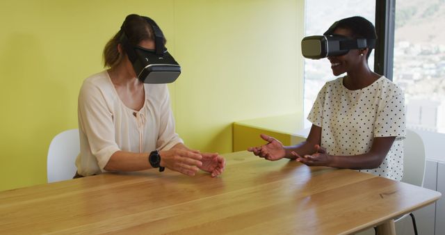 Two diverse coworkers using VR headsets seated at a wooden table in modern office. They are interacting with virtual objects. Useful for illustrating cutting-edge technology, workplace innovation, collaboration tools, and VR applications in professional settings.