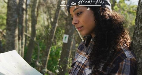 Young woman navigating in forest while contemplating