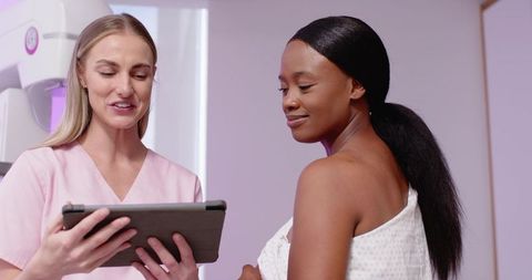 Nurse showing mammogram scan on tablet to African American patient breast screening