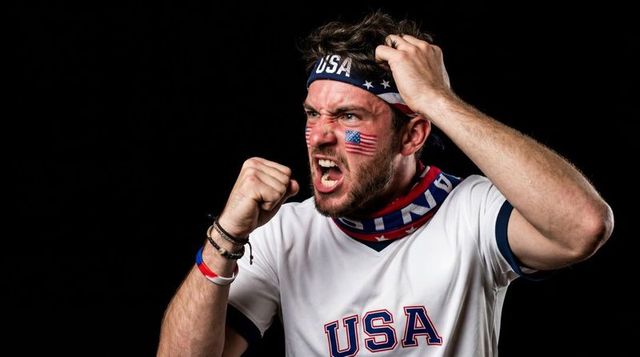Shouting usa sports fan clenching fist wearing headband, face paint, patriotic gaiter