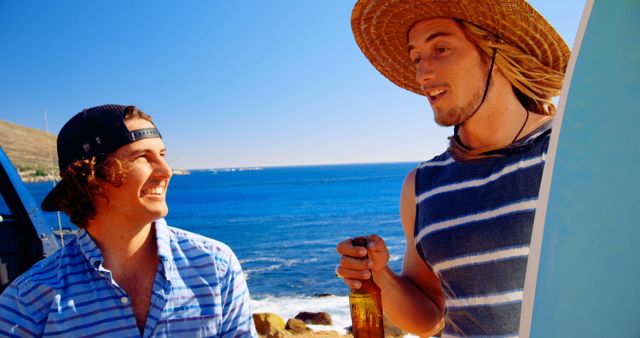 Two friends enjoy a sunny beach day, chatting while holding beers and surfboards against a backdrop of ocean waves and a clear blue sky. Perfect for themes of summer relaxation, friendship, leisure activities, and coastal lifestyles.